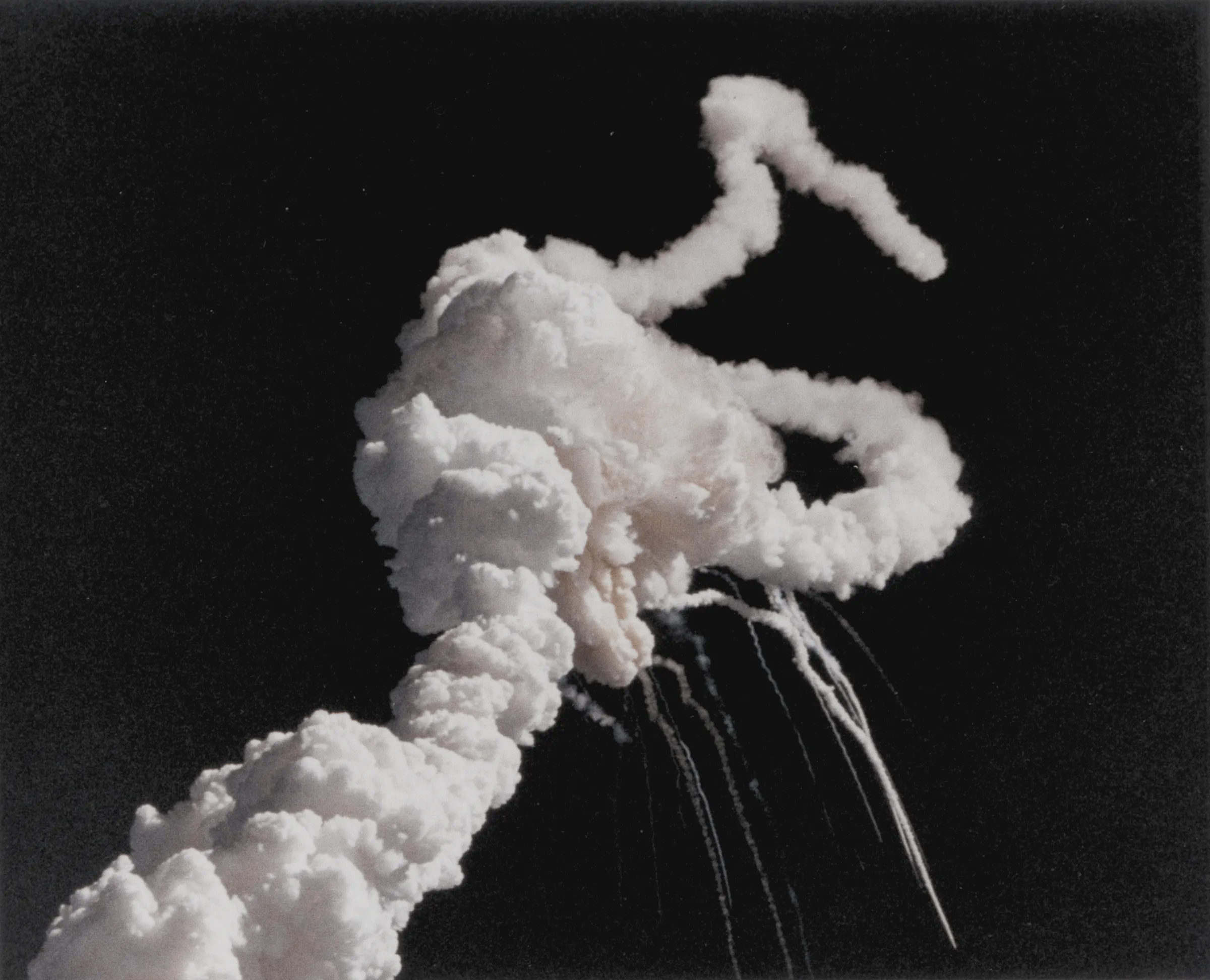 The plume of smoke from the space shuttle Challenger over Florida on 28 January 1986, the two solid rocket boosters spiralling away from it and debris trailing below.