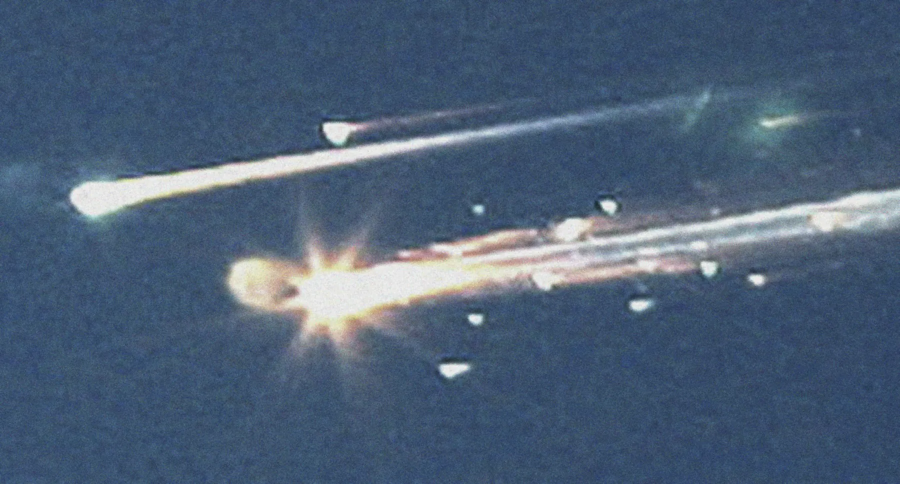 Pieces of the space shuttle Columbia streaking across a blue sky over Tyler, Texas, on 1 February 2003, each a bright point trailing a long white plume.