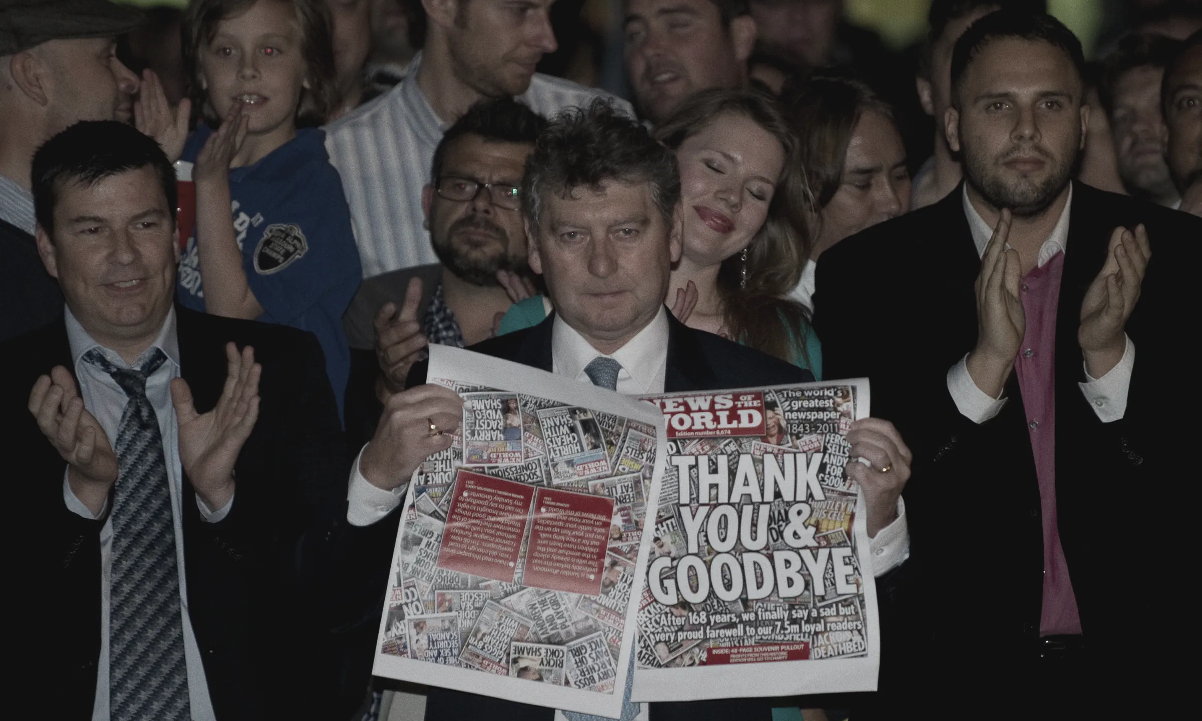 News of the World editor Colin Myler, surrounded by applauding staff, holds up the paper's final edition, headlined "Thank you & goodbye", outside its offices on 9 July 2011.